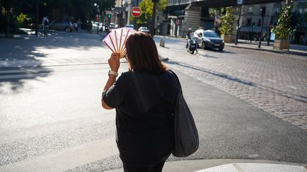 Une femme s'abrite du soleil lors d'un épisode de canicule, le 8 septembre 2023, à Paris. (LAURE BOYER / HANS LUCAS / AFP)