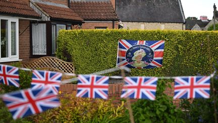 Un portrait d'Elizabeth II et des drapeaux britanniques installés&nbsp;dans le cadre du jubilé de la reine à Masham, en Angleterre. (OLI SCARFF / AFP)