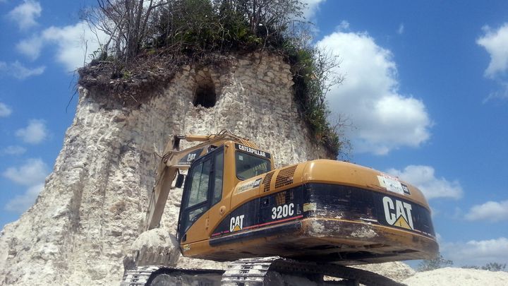 Un bulldozer devant la pyramide Maya du site Noh Mul (Belize), le 10 mai. La pyramide, haute de 30 m&egrave;tres, a &eacute;t&eacute; r&eacute;duite &agrave; un amas de d&eacute;bris. (JULES VASQUEZ / AFP)