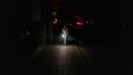 A woman walks in the dark, during a blackout after strikes on energy infrastructure, on June 5, 2024 in kyiv (Ukraine).  (ROMAN PILIPEY / AFP)