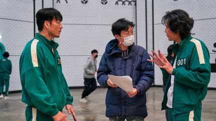 Le réalisateur Hwang Dong-hyuk (au centre) parle avec l'acteur Lee Jung-jae (à droite) pendant une scène de la première saison de la série sud-coréenne "Squid Game". (AFP PHOTO / NETFLIX)