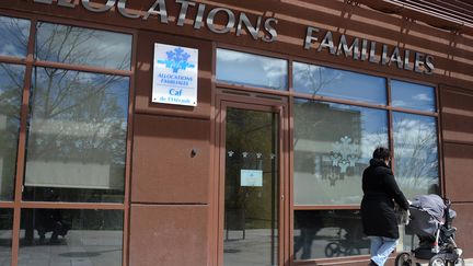 Une femme marche avec un enfant dans une poussette devant le bureau des allocations familiales &agrave; Montpellier (H&eacute;rault), le 2 avril 2013. (PASCAL GUYOT / AFP)