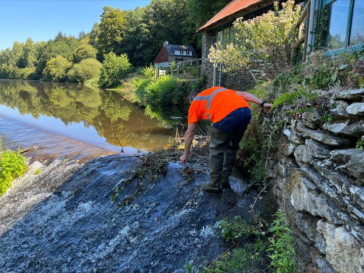 Pierre-Antoine Rousseau cleans a weir by removing branches that obstruct the flow of the river.  (BENJAMIN RECOUVREUR / RADIO FRANCE)