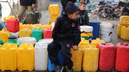 A Palestinian child sits on water cans on March 31, 2024, in Gaza City.  (AFP)