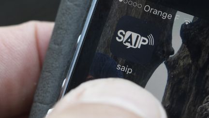 Le logo de l'application SAIP (Système d'alerte et d'information aux populations) sur un téléphone portable, en juin 2016. (DAMIEN MEYER / AFP)