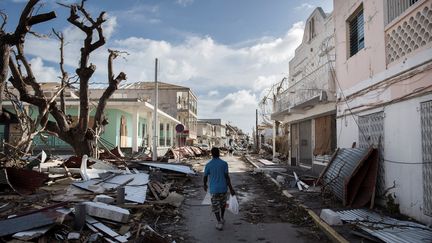 Un homme traverse, au milieu des débris, une rue dans un village près de Marigot (Saint-Martin), le 8 septembre 2017. (MARTIN BUREAU / AFP)