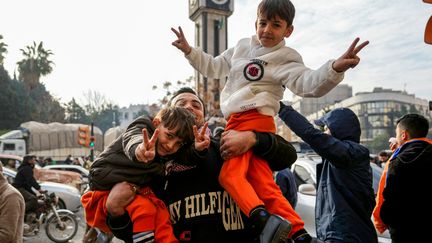 Une famille se réjouit de la chute de Bachar al-Assad, près de la tour de l'horloge de Homs, dans le centre de la Syrie, le 8 décembre 2024. (MUHAMMAD HAJ KADOUR / AFP)