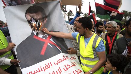 Des manifestants Lybiens brûlent une affiche d'Emmanuel Macron lors d'un rassemblement contre le maréchal Khalifa Haftar, à Tripoli. (FADEL SENNA / AFP)