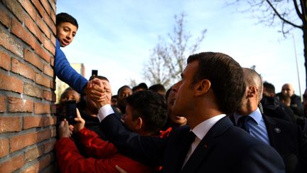 Emmanuel Macron serre la main d'un jeune garçon à Amiens (Somme), le 22 novembre 2019. (CHRISTOPHE ARCHAMBAULT / AFP)