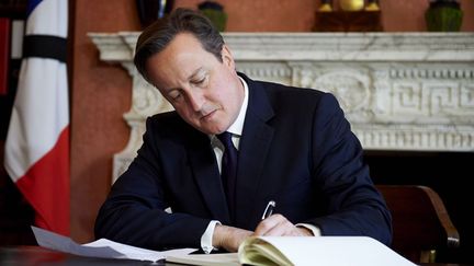 «Nous sommes solidaires avec vous», «Nous sommes tous ensemble», écrit le Premier ministre britannique, en français dans le texte, sur les pages du registre de condoléances, en hommage aux victimes des attentats de Paris le 13 novembre. David Cameron a aussi décidé d'assister au match amical Angleterre-France le 17 au soir, où il est prévu une minute de silence et le chant de l'hymne national français, La Marseillaise. (Niklas HALLE&#039;N / AFP PHOTO )