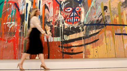 Cheyenne Westphal, présidente de Phillips, pose avec une œuvre intitulée "Untitled, 1982" de l'artiste américain Jean-Michel Basquiat, estimée à 70 millions de dollars, lors d'un photocall avant sa vente, à la maison de vente aux enchères Phillips à Londres le 28 février 2022 (TOLGA AKMEN / AFP)