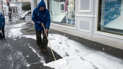 Un parisien d&eacute;neigeant un trottoir, mardi 12 mars 2013. (FRED DUFOUR / AFP)