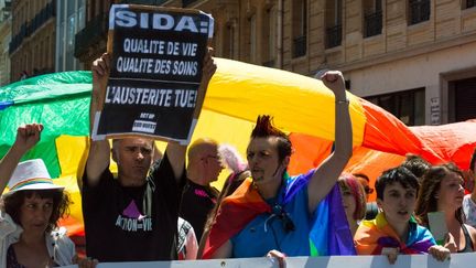 Un participant à la Gay Pride de Toulouse (Haute-Garonne) &nbsp;brandit une affiche pour alerter sur la dégradation des soins apportés aux malades du&nbsp;sida, le 20 juin 2015 (CLEMENT GRUIN / CITIZENSIDE.COM / AFP)