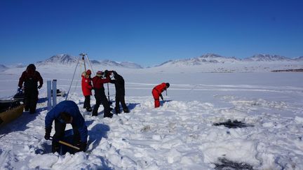 Des scientifiques pratiquent des forages dans la glace du lac Hazen, dans l'extrême nord du Canada, le 29 mai 2017.&nbsp; (GRAHAM COLBY / AFP)