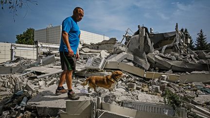 Un homme&nbsp;sur les décombres d'un bâtiment&nbsp;à la suite d'une frappe de missile dans la ville de Derhachi, dans la région de Kharkiv, le 26 août 2022. (SERGEY BOBOK / AFP)