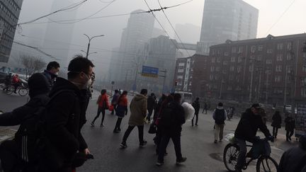 Des passants portent des masques pour se protéger de la pollution à Pékin (Chine), le 14 décembre 2015. (GREG BAKER / AFP)