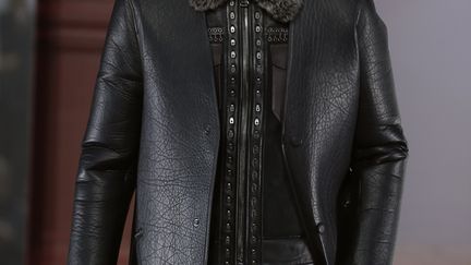 Lanvin a proposé des pantalons larges à taille haute, des pulls à torsades rentrés sous la ceinture, des vestes de costumes croisés. Les chemises s'accompagnent de sous-pulls. Les pièces se superposent: un blouson en serpent se porte sur une veste de costume Prince de Galles. Un pardessus recouvre une longue veste en cuir, qui elle-même s'additionne à trois couches de vêtements. Les formes sont amples, la palette dominée par le gris. Les dernières silhouettes, noires, sont accessoirisées par des épingles. "Le métal (des épingles) était important, ce côté dur. Nous vivons dans une époque difficile, ça oblige le designer à se poser des questions sur son travail", a commenté le directeur artistique pour la ligne masculine de Lanvin, Lucas Ossendrijver. "Quand on regarde à Paris, il y a tellement de militaires en ce moment, ça a un côté surréaliste". "J'ai de la chance de pouvoir rêver, d'avoir la possibilité des faire les choses que je veux, tout en restant quand même dans une sorte de réalité", a-t-il ajouté.
 (PATRICK KOVARIK / AFP)