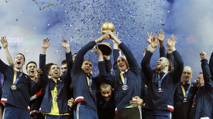 Le gardien de but Thierry Omeyer et le demi-centre Daniel Narcisse soulèvent le trophée des Mondiaux de handball,&nbsp;après la victoire de l'équipe de France face à la Norvège 33 à 26, à&nbsp;l’Arena de Bercy (Paris), le 29 janvier 2017. (THOMAS SAMSON / AFP)