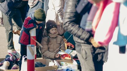 Des enfants ukrainiens piochent parmi les dons de Polonais, devant la gare routière de Varsovie, le 2 mars 2022.&nbsp; (PATRYK NOGAL / FRANCE INFO)