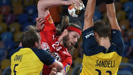 Mikkel Hansen passe en force entre deux Suédois lors de la finale du Mondial le 31 janvier 2021 (ANNE-CHRISTINE POUJOULAT / AFP)