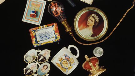 Une centaine d'objets commémoratifs à l'effigie de la Reine Elizabeth II : les enseignes et artisans sont à l'oeuvre depuis des mois.&nbsp; (TONY EVANS/TIMELAPSE LIBRARY LTD / HULTON ARCHIVE / GETTY IMAGES)