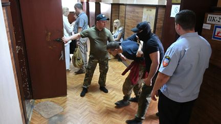 Un combattant étranger de nationalité marocaine est escorté au tribunal par les forces de l'ordre de la république autoproclamée de Donetsk, le 9 juin 2020. (KONSTANTIN MIHALCHEVSKIY / SPOUTNIK / AFP)