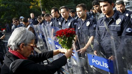 Une manifestante tendant des fleurs aux policiers charg&eacute;s d'encadrer la manifestation &agrave; Ankara (Turquie), le 11 octobre 2015.&nbsp; ( UMIT BEKTAS / REUTERS)