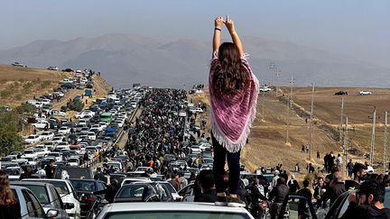 Image postée sur Twitter, le 26 octobre 2022. Une femme debout sur une voiture, dans un cortège de milliers de manifestants se dirigeant vers le cimetière Aichi de Saqez, en Iran, le village de Mahsa Amini, 22 ans, morte le 16 septembre, après avoir été battue à mort par la police des mœurs iranienne, qui l'avait arrêtée pour "port de vêtements inappropriés". (AFP / UGC)