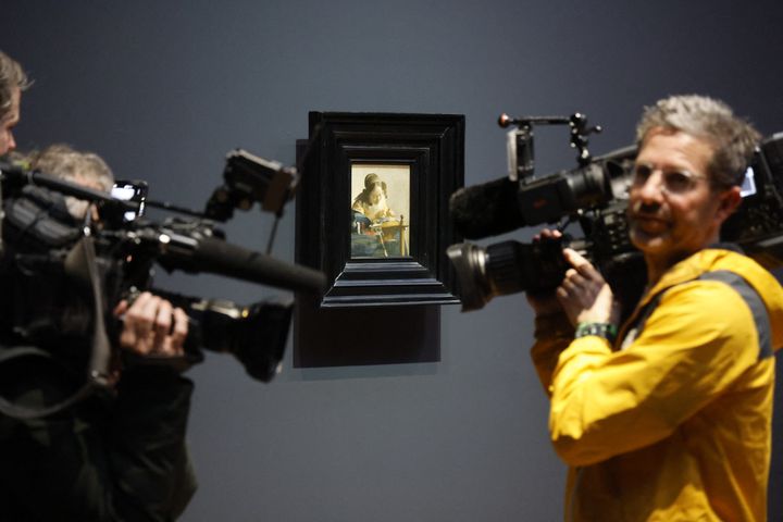 Les caméras de télévision à côté du tableau "La Dentellière" de Johannes Vermeer, lors de l'exposition dédiée au peintre néerlandais au Rijskmuseum d'Amsterdam en avril 2023 (LUDOVIC MARIN / AFP)