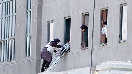 Une femme est évacuée du parlement iranien le 7 juin 2017 à Téhéran, alors que le bâtiment est attaqué par un commando terroriste. (- / DPA / AFP)