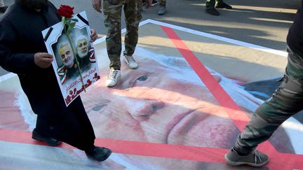 Un portrait du président américain Donald Trump piétiné le 6 janvier 2020 à Bagdad (Irak), lors d'une procession en hommage au général iranien Qassem Soleimani, tué par une frappe américaine sur la capitale irakienne. (AHMAD AL-RUBAYE / AFP)