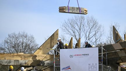 Des charpentiers travaillent sur l'assemblage à blanc de la nouvelle flèche de Notre-Dame de Paris, à Briey, en Lorraine, le 16 mars 2023. (JEAN-CHRISTOPHE VERHAEGEN / AFP)