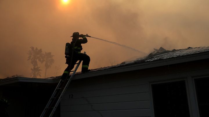 Un pompier arrose la toiture d'une maison en feu à Altadena (Californie, Etats-Unis), le 9 janvier 2025. (JUSTIN SULLIVAN / GETTY IMAGES NORTH AMERICA / AFP)