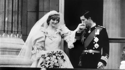 Le prince Charles baise la main de son &eacute;pouse Diana sur le balcon de Buckingham Palace &agrave; Londres (Royaume-Uni) apr&egrave;s leur mariage, le 29 juillet 1981. (ARCHIVE / UPI / AFP)