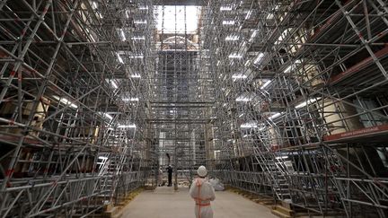 Un ouvrier se tient sous un échafaudage sur le&nbsp;chantier de la cathédrale Notre-Dame à Paris, le 15 avril 2022. (IAN LANGSDON / AFP)