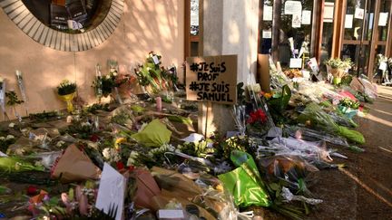 Des fleurs sont déposées devant l'entrée d'un collège de Conflans-Sainte-Honorine (Yvelines) en hommage à Samuel Paty, le 17 octobre 2020. La veille, le professeur d'histoire-géographie avait été assassiné par un terroriste qui lui reprochait d'avoir montré à ses élèves des caricatures du prophète Mahomet. (BERTRAND GUAY / AFP)