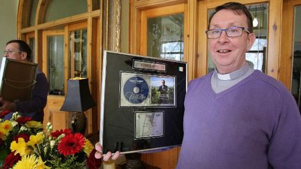 Le prêtre chanteur irlandais Ray Kelly, à son domicile, avec son disque de platine pour son premier album, en avril 2015.
 (PAUL FAITH / AFP)