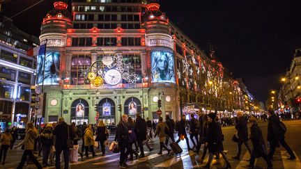 Des passants marchent devant le magasin Printemps illuminé pour les fêtes de fin d'années, à Paris, le 22 décembre 2015. (IRINA KALASHNIKOVA / RIA NOVOSTI/ AFP)