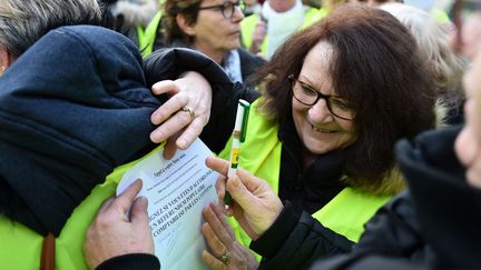 Des manifestants "gilets jaunes" signent une pétition en faveur d'un référendum populaire réclamant la destitution du président français alors qu'ils participaient à une marche civique au Mans (Sarthe), le 24 novembre 2018. (JEAN-FRANCOIS MONIER / AFP)