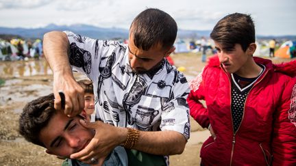 Un migrant se fait couper les cheveux sur le camp d'Idomeni, le 8 mars. (ZOLTAN BALOGH / MTI)