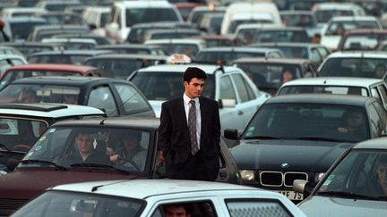 Dans les rues de Paris, les jours de grève se suivent et se ressemblent.&nbsp;Au milieu de voitures qui avancent pare-choc contre pare-choc, ce 1er décembre 1995, un piéton semble résigné. (HALEY / SIPA)