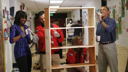 Le pr&eacute;sident Barack Obama et son &eacute;pouse Michelle, peignent une &eacute;tag&egrave;re avec des volontaires dans une &eacute;cole, dans le cadre d'une journ&eacute;e du volontariat, le 19 janvier 2013.&nbsp; (KEVIN LAMARQUE / REUTERS)