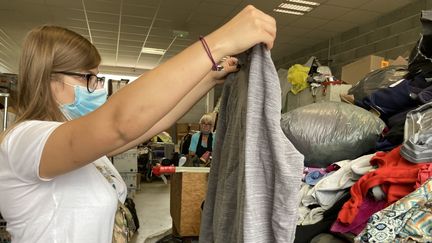 Dagmara, une jeune Polonaise, trie des vêtements donnés à la Communauté d'Emmaüs de Pamiers, en Ariège. (MATHILDE ANSQUER / RADIO FRANCE)