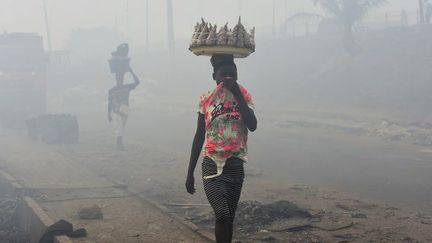 Les vendeurs se couvrent le nez pour marcher dans les décharges du site d'Olusosun à Ojota, près de Lagos, capitale commerciale du Nigeria, le 22 mars 2018. Le gouvernement a fermé le site après un incendie dû à une flambée de gaz piégés. (PIUS UTOMI EKPEI/AFP)