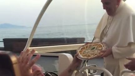 Vincenzo Cacialli est parvenu &agrave; remettre une pizza au pape Fran&ccedil;ois, tandis que ce dernier progressait &agrave; bord de sa papamobile sur le front de mer de Naples (Italie), samedi 21 mars 2015. (ANTONIO GRECO / YOUTUBE)