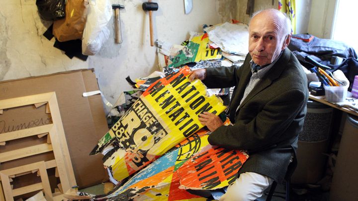 L'artiste Jacques Villeglé, le 3 septembre 2008, dans son atelier à Paris,
avec l'une de ses célèbres affiches lacérées. Celui que l'on désigne comme le pionnier du street art est mort le 7 juin, à 96 ans.&nbsp; (PATRICK KOVARIK / AFP)