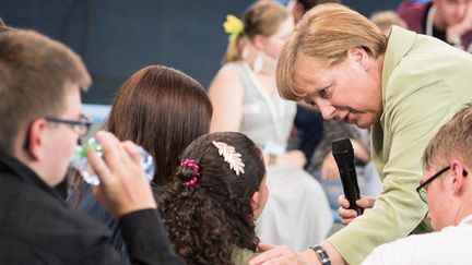 Angela Merkel tente de réconforter une jeune Palestinienne à Rostock. (STEFFEN KUGLER / DPA / DPA PICTURE-ALLIANCE/AFP)