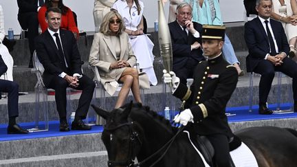 Le chef des écuyers du Cadre Noir de Saumur et médaillé d'or à Rio en 2016 Thibaut Vallette tient le flambeau de la flamme olympique lors du défilé militaire du 14-Juillet, le long de l'avenue Foch à Paris le 14 juillet 2024. (JULIEN DE ROSA / AFP)