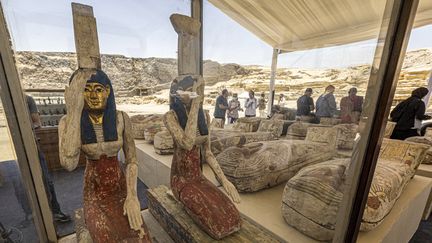 Des statuettes représentant les déesses égyptiennes (de gauche à droite) Isis et Nephthys et d'autres sarcophages trouvés dans la cache datant de la Basse Époque égyptienne,&nbsp;exposés après leur découverte, au cimetière de Bubastian dans la nécropole de Saqqarah, au sud-ouest de la capitale égyptienne, le 30 mai 2022.&nbsp; (KHALED DESOUKI / AFP)