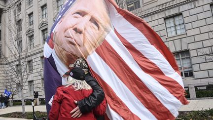 Un couple de partisans de Donald Trump tenant un drapeau américain à l'image du président sortant, le 6 janvier à Washington (J.M. GIORDANO / MAXPPP)